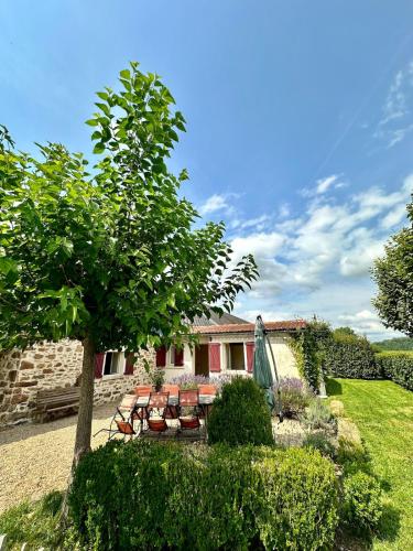 a garden with chairs and a umbrella and a house at Aux Détours de l'Étang La Bergerie et sa piscine privative in Château-Chervix