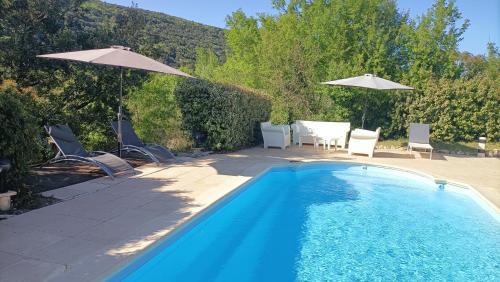 una piscina con sedie e ombrelloni in un cortile di Le Paradis de l'Ibie a Saint-Maurice-dʼIbie