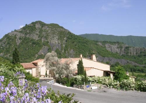 a house in front of a mountain with purple flowers at La Lavande in La Robine