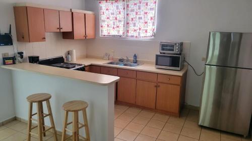 a kitchen with a refrigerator and two bar stools at Brisas de Campo in Aguadilla