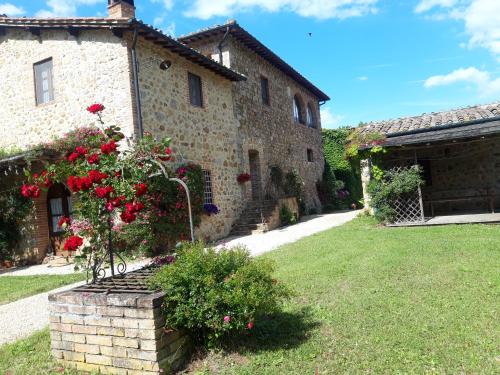 a stone building with red flowers in a yard at Castellare in Chiusdino
