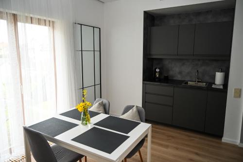 a kitchen with a white table with chairs and a vase of flowers at Domus Revado in Birštonas