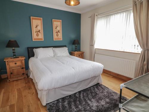 a bedroom with a large white bed and a window at Donagh Cross Town House in Carndonagh