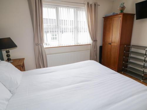 a bedroom with a white bed and a window at Donagh Cross Town House in Carndonagh