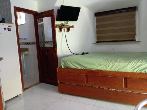 a bedroom with a bed and a shower and a television at Chalé em Búzios 100m da Praia de Tucuns in Búzios