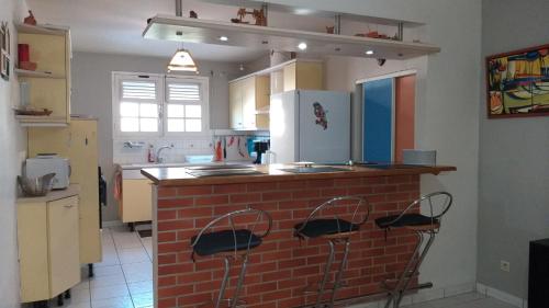 a kitchen with a brick counter with two stools at Grand F2, spa, jardin, parking in Schœlcher