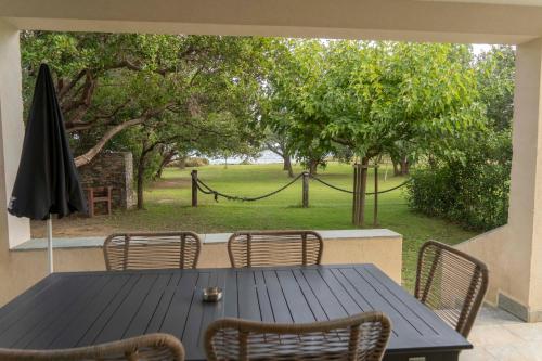 une table avec des chaises et un parasol sur une terrasse dans l'établissement Residence Scopa Marina, à Poggio-Mezzana