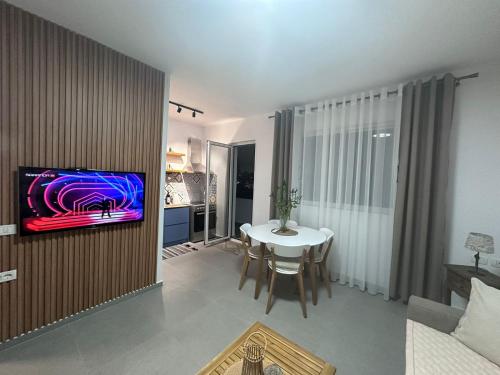 a living room with a table and a tv on a wall at Florentina Apartments in Sarandë