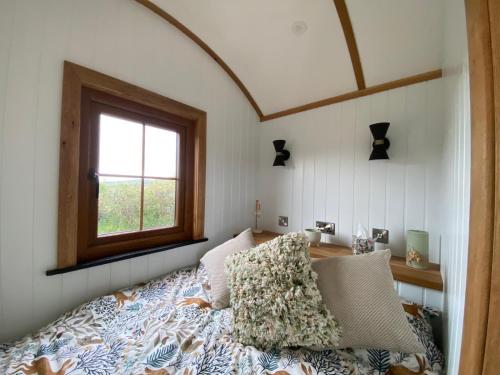 a bedroom with a bed with a window at Aberdaron Shepherd Huts in Aberdaron