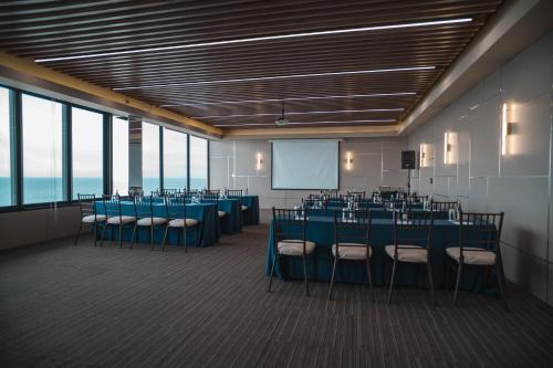 a conference room with tables and chairs and a screen at MantaHost Hotel in Manta