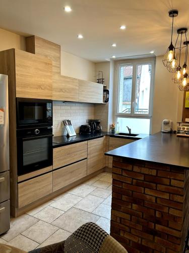 une cuisine avec des armoires en bois et un comptoir noir dans l'établissement Maison de ville, Gien centre, à Gien