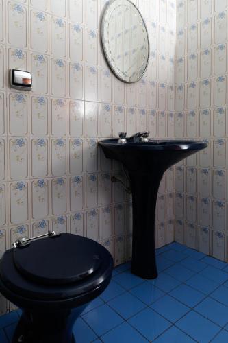 a bathroom with a black toilet and a mirror at Hostel Junqueira in Tatuí