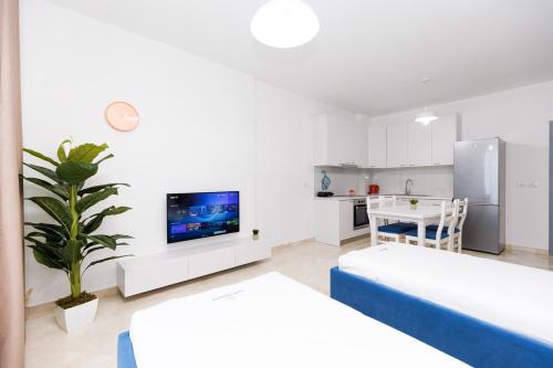 a white living room with a tv and a kitchen at CAPTAIN'S RESIDENCE in Ksamil