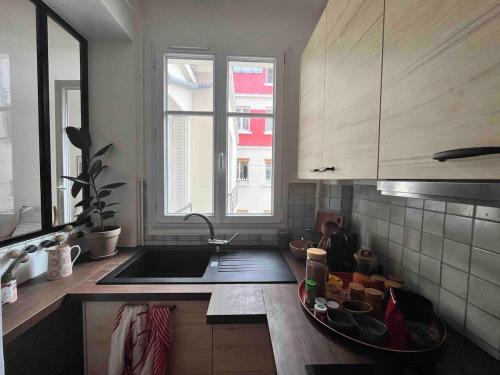 d'une cuisine avec un comptoir, un évier et une fenêtre. dans l'établissement Charmant 2 pièces dans le quartier chic du Parc des Princes, à Boulogne-Billancourt