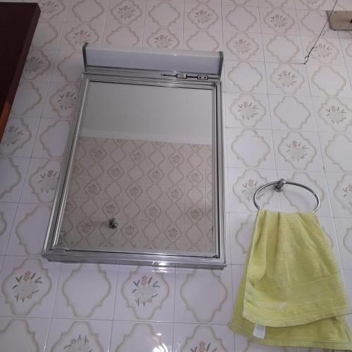 a mirror on a bathroom wall with a yellow towel at Hostel Junqueira in Tatuí