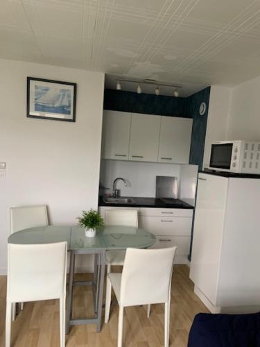 une cuisine avec une table et des chaises et un micro-ondes dans l'établissement appartement 50 m plage st Jean de Monts, à Saint-Jean-de-Monts