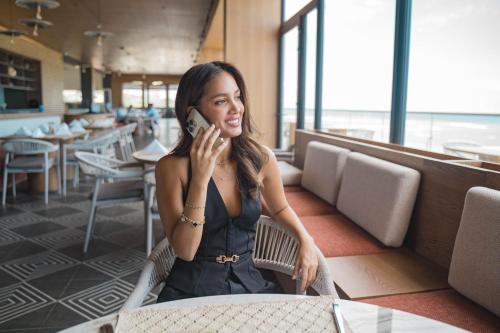 a woman sitting in a restaurant talking on a cell phone at MantaHost Hotel in Manta