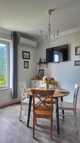 a dining room with a table and chairs and a tv at Apartment Mint&Rose in Risan