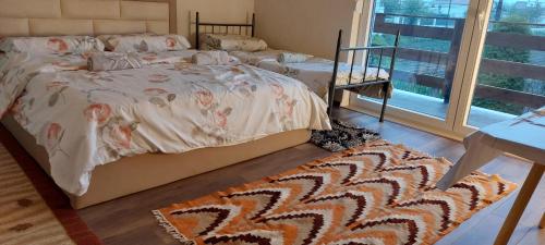 a bedroom with a bed and a rug and a window at Villa Nathanael Cozy Rooms with Balcony in Pogradec