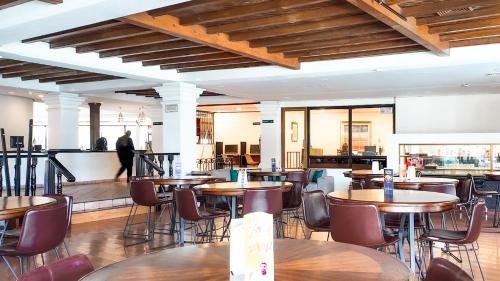 a restaurant with tables and chairs and a person in the background at InHouse Hotel Obregón in Ciudad Obregón
