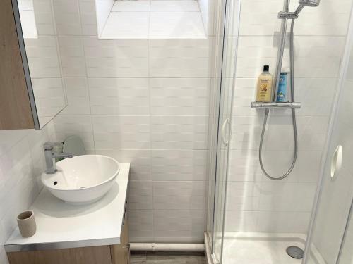 a white bathroom with a sink and a shower at Studio lumineux et calme - Netflix, CHU et métro 14 in Le Kremlin-Bicêtre