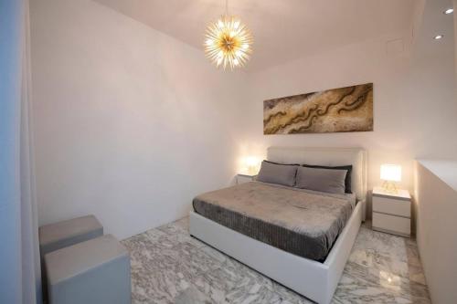 a white bedroom with a bed and a chandelier at La Galleria in Milan