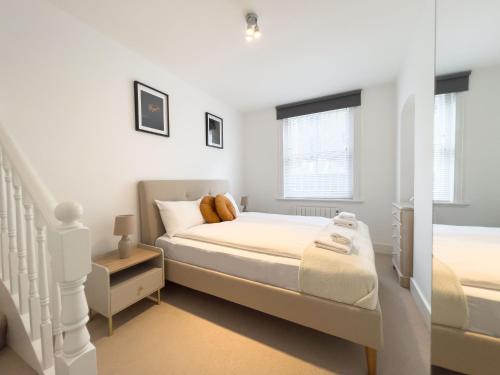 ein weißes Schlafzimmer mit einem Bett und einer Treppe in der Unterkunft The Fitz Central Apartment in London