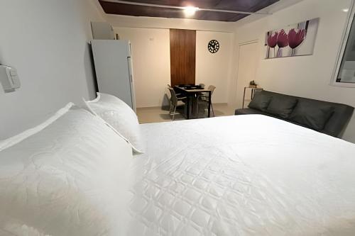 a large white bed in a room with a couch at Apartamento cerca a la playa y al mar Punta Roca in Maizal