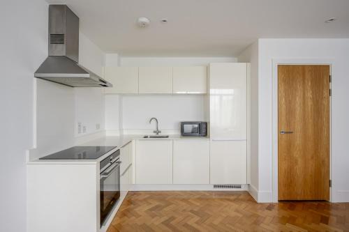 a white kitchen with a sink and a microwave at Luxurious City Centre Apartment in Chelmsford with Sky Sports & Movies in Chelmsford