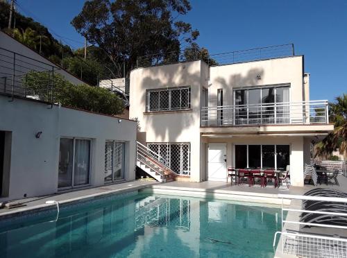 une maison blanche avec une piscine devant dans l'établissement Cannes Super Cannes Golfe-Juan - Vue mer exceptionnelle méditerranée Cap d'Antibes- Villa Alamp - 4 à 6 chambres 6 sdb 7 wc - piscine - Superbe rooftop sans vis-à-vis - grand living - Possibilité Courts séjours -, à Vallauris