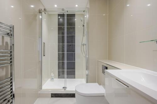 a white bathroom with a shower and a toilet at Luxurious City Centre Apartment in Chelmsford with Sky TV, Sports, Movies & Netflix in Chelmsford