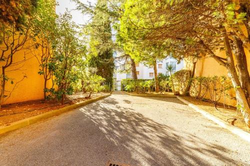 une rue vide avec des arbres et un bâtiment jaune dans l'établissement A Deux pas de la Mer, à Bandol