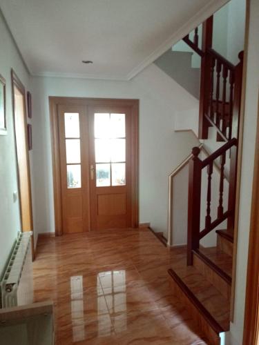 an empty room with a wooden door and stairs at Casa El Campo in Oruña