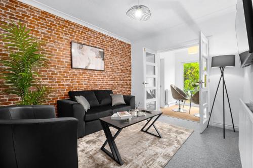 a living room with a black couch and a brick wall at Stylish Four Bedroom House - Garden - Parking - Great Barr 110F in Birmingham