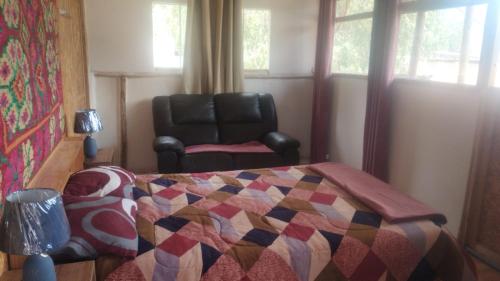 a bedroom with a bed and a leather chair at LA CASA DE RICKY "El balcón de las Montañas" in Caraz