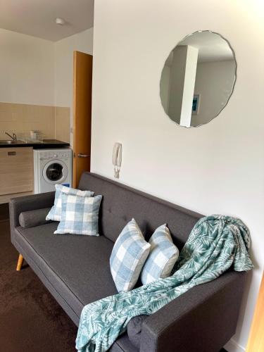 a living room with a couch with pillows and a mirror at Chic Trafford Apartment, Private Underground Parking, Fast Wi-Fi, Self Check-in Anytime, 5 mins to Old Trafford Stadium in Manchester