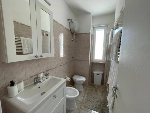 a white bathroom with a sink and a toilet at Villa Incanto Pina - Torre Canne in Torre Canne