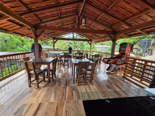 a restaurant with wooden tables and chairs on a deck at Hostal la Divisa Salento in Arrayanal
