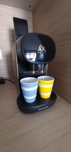 une cafetière avec deux tasses sur une table dans l'établissement 2 pièces avec terrasse -Calme-Sans vis à vis-garage-centre de Cannes, à Cannes