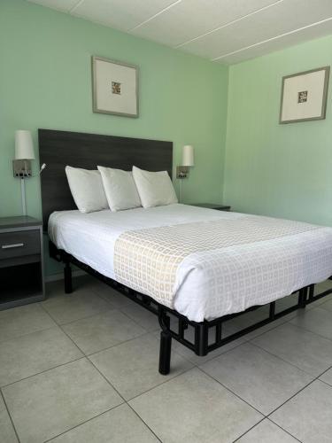 a bedroom with a large bed with white sheets and pillows at Royal Canadian Motel in Wildwood