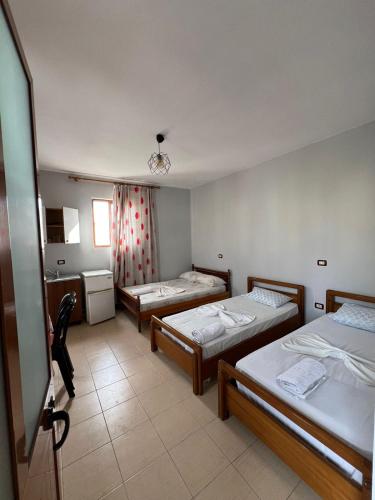 a room with three beds in it with a kitchen at Begaj Rooms in Durrës