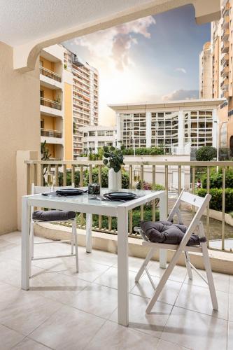une table et une chaise blanches sur un balcon avec des bâtiments dans l'établissement Qult - Blue Lagoon - 10 min to Casino, à Beausoleil