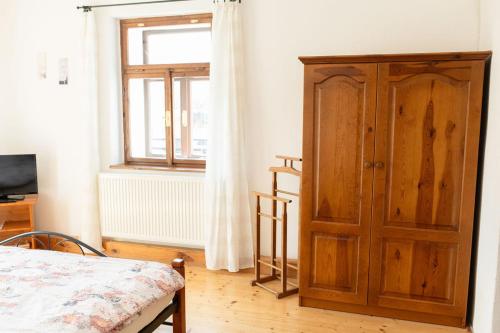 a bedroom with a wooden cabinet and a window at Mlýn Kamenice in Klučenice