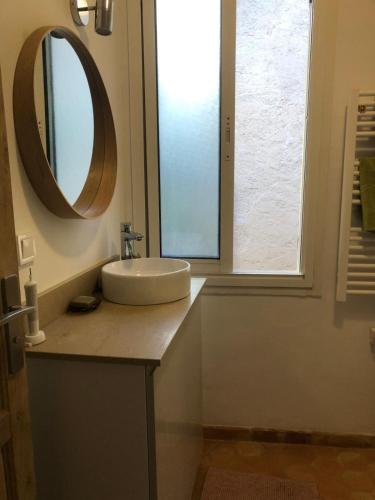 une salle de bain avec un lavabo et un miroir sur un comptoir dans l'établissement Maison La Paillère, village, à Villeneuve-Loubet