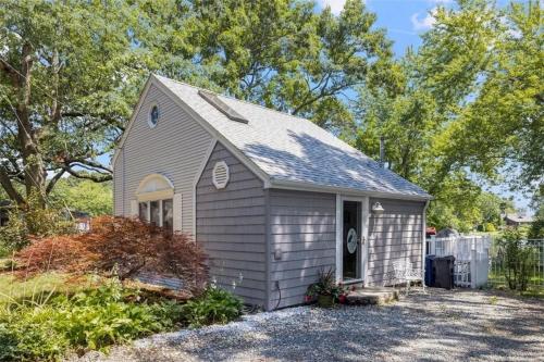 a small house in a yard with trees at Cozy Waterfront Cottage - Sleeps 4 in Warwick