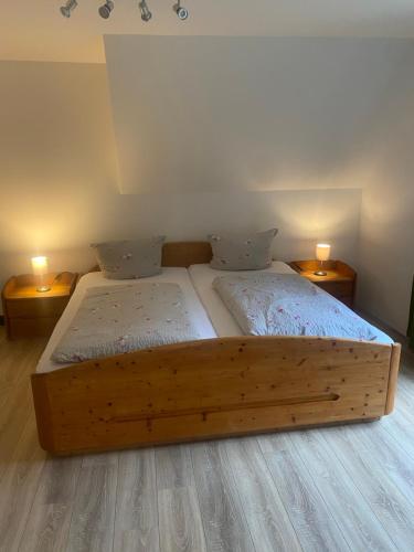 a wooden bed in a room with two lamps at Ferienhof Kröger in Bielefeld