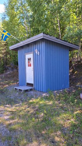 a blue shed with a bench in a field at Lakeview Houses Sweden in Falun