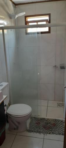 a bathroom with a toilet and a glass shower at Casa de praia em garopaba sc in Garopaba