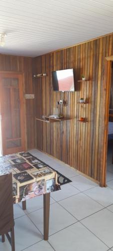 a room with a table and a tv and wooden walls at Casa de praia em garopaba sc in Garopaba