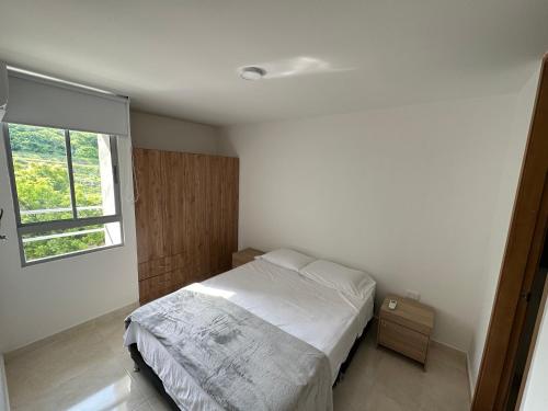 a bedroom with a white bed and a window at Apto con vista verde y aire acondicionado in Barranquilla